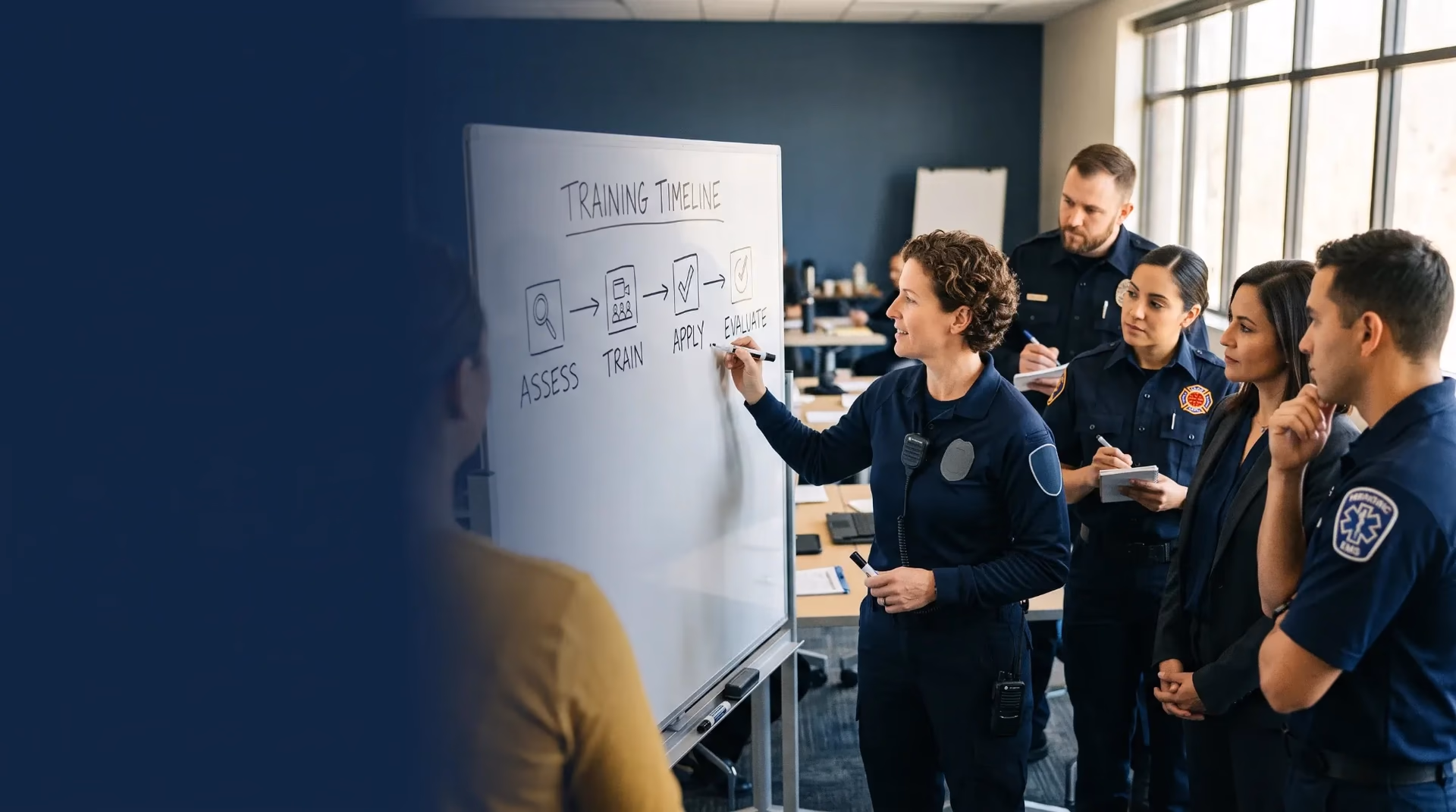 An instructor sketches a four-step training timeline on a whiteboard for a cohort of public-safety leaders